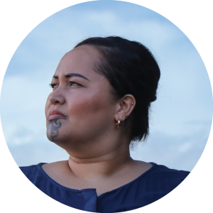 A Maori lady with a moko (traditional new zealand facial tattoo) with a blue cloudy sky behind her.