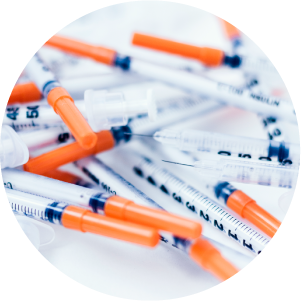 Pile of medical syringes on white table.