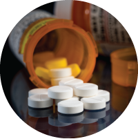 Macro of oxycodone opioid tablets with prescription bottles against dark background.