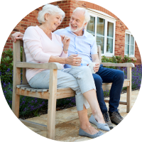 Photo of elderly man and woman sitting on bench.